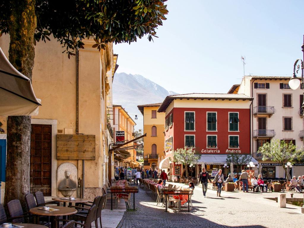 city street with cafes and outdoor seating while people enjoy the beautiful sunny day with mountains in the background
